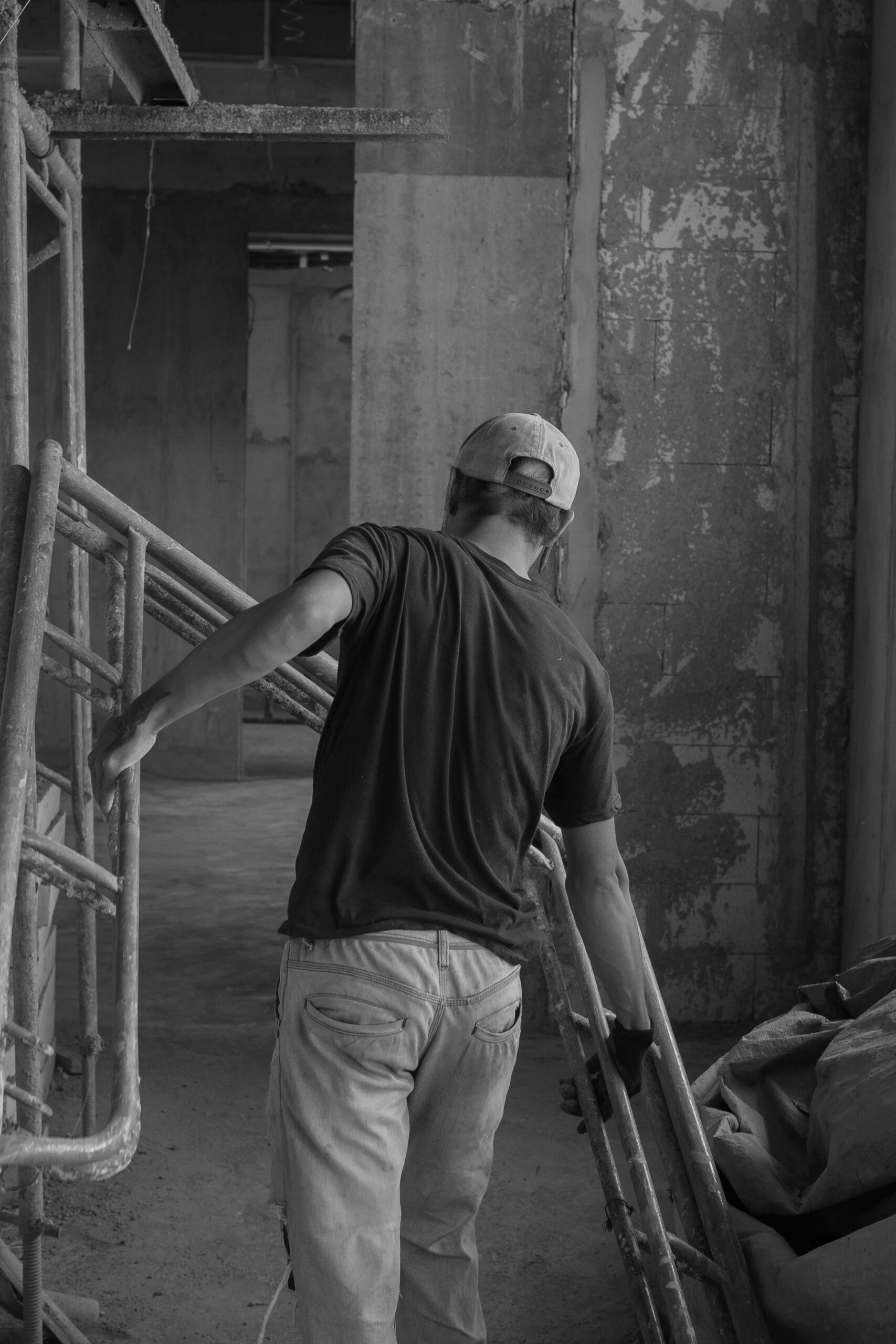 O nas Worker adjusting scaffolding in an industrial indoor setting captured in monochrome.